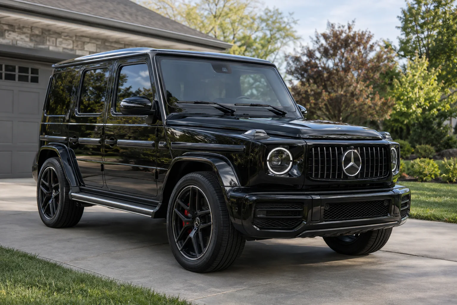 A black Mercedes G-Class with tinted windows on a home driveway