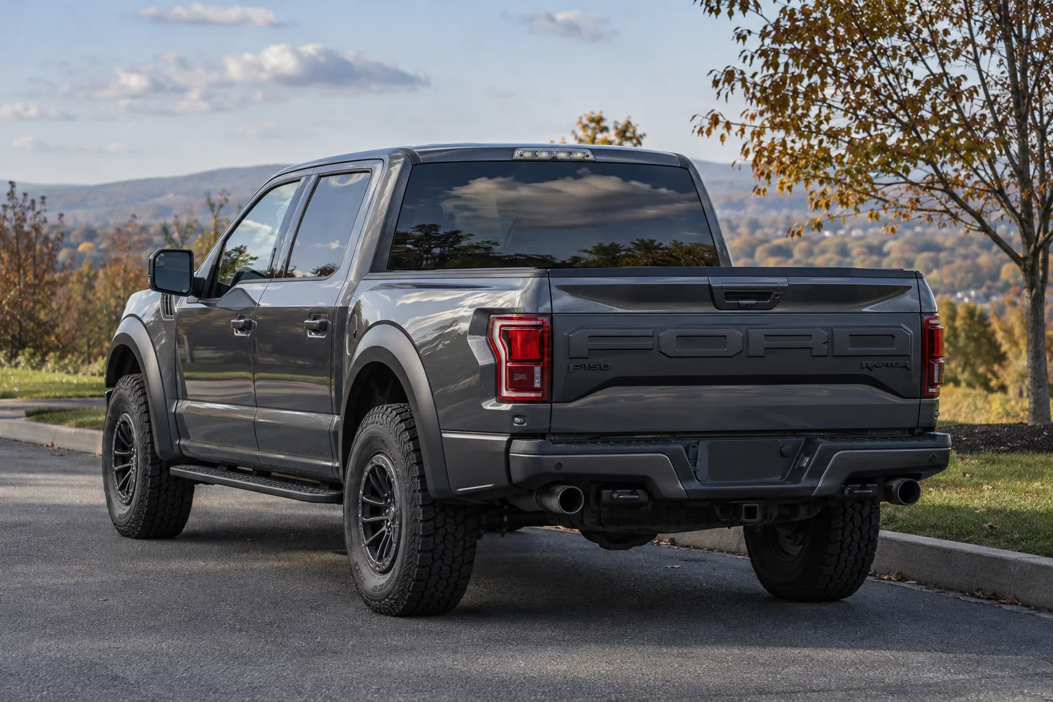 A gray Ford pickup with tinted rear glass parked above a valley
