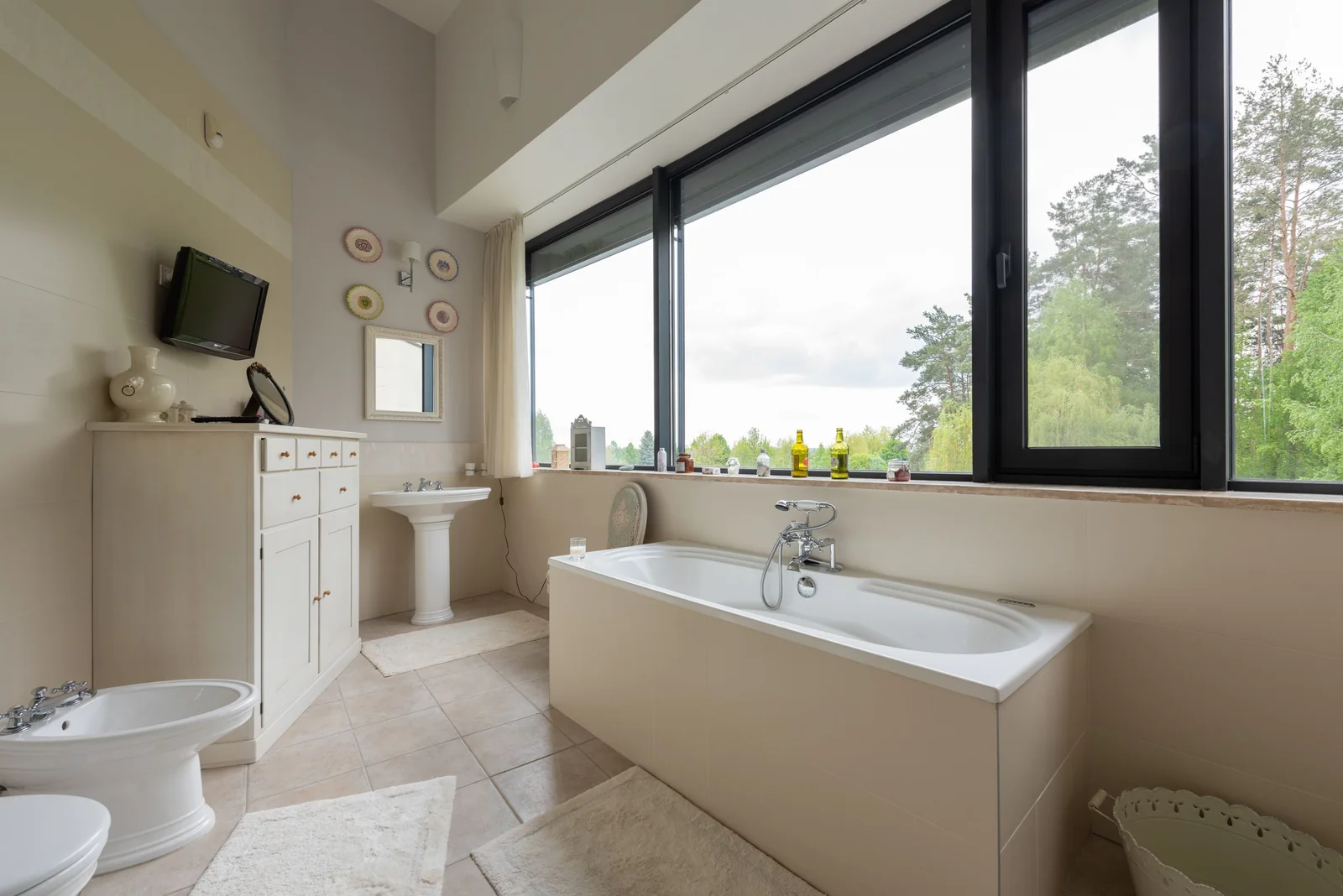 A bathroom with a large window looking out on trees
