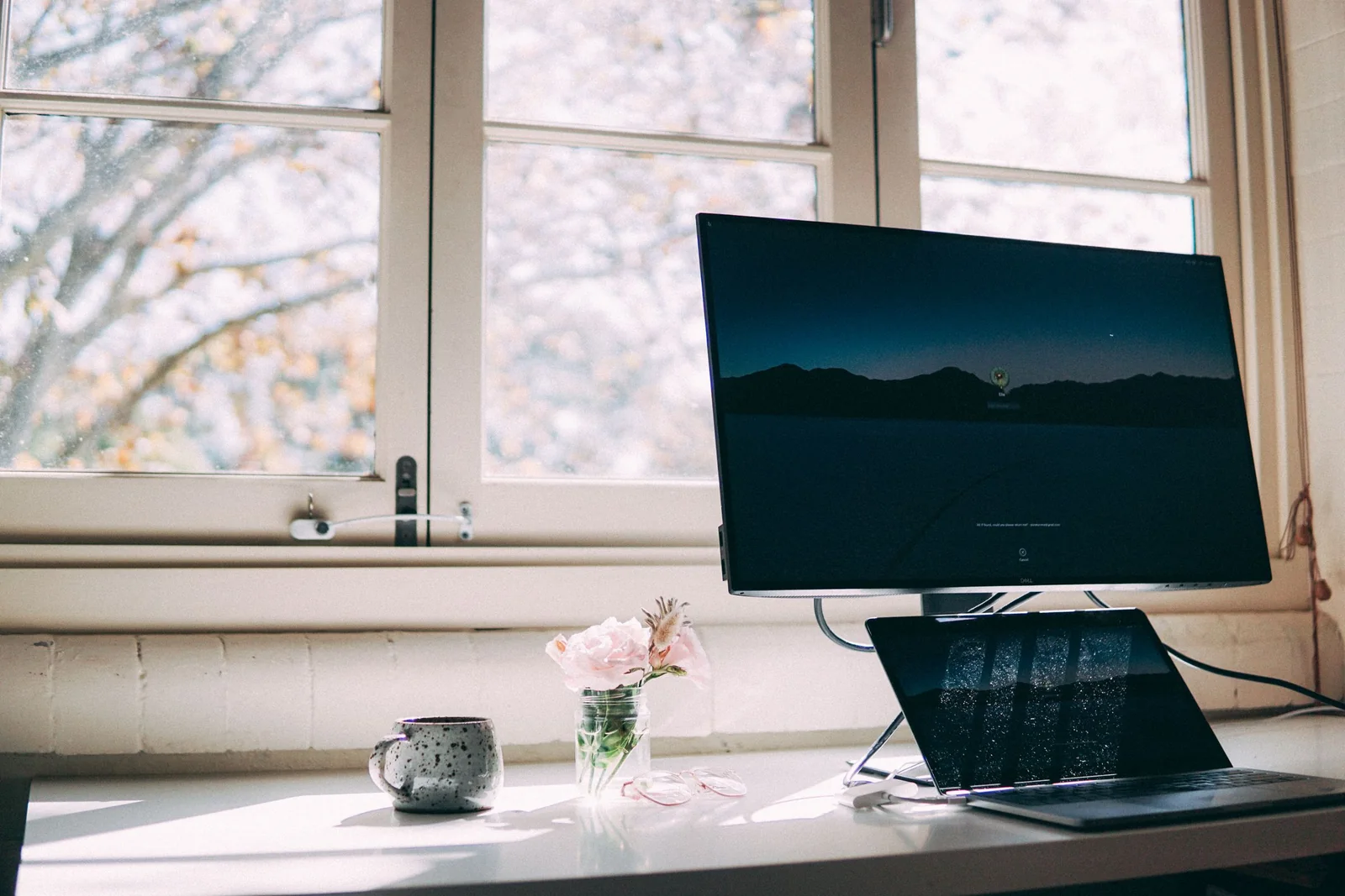A desk and computer screen beside a window