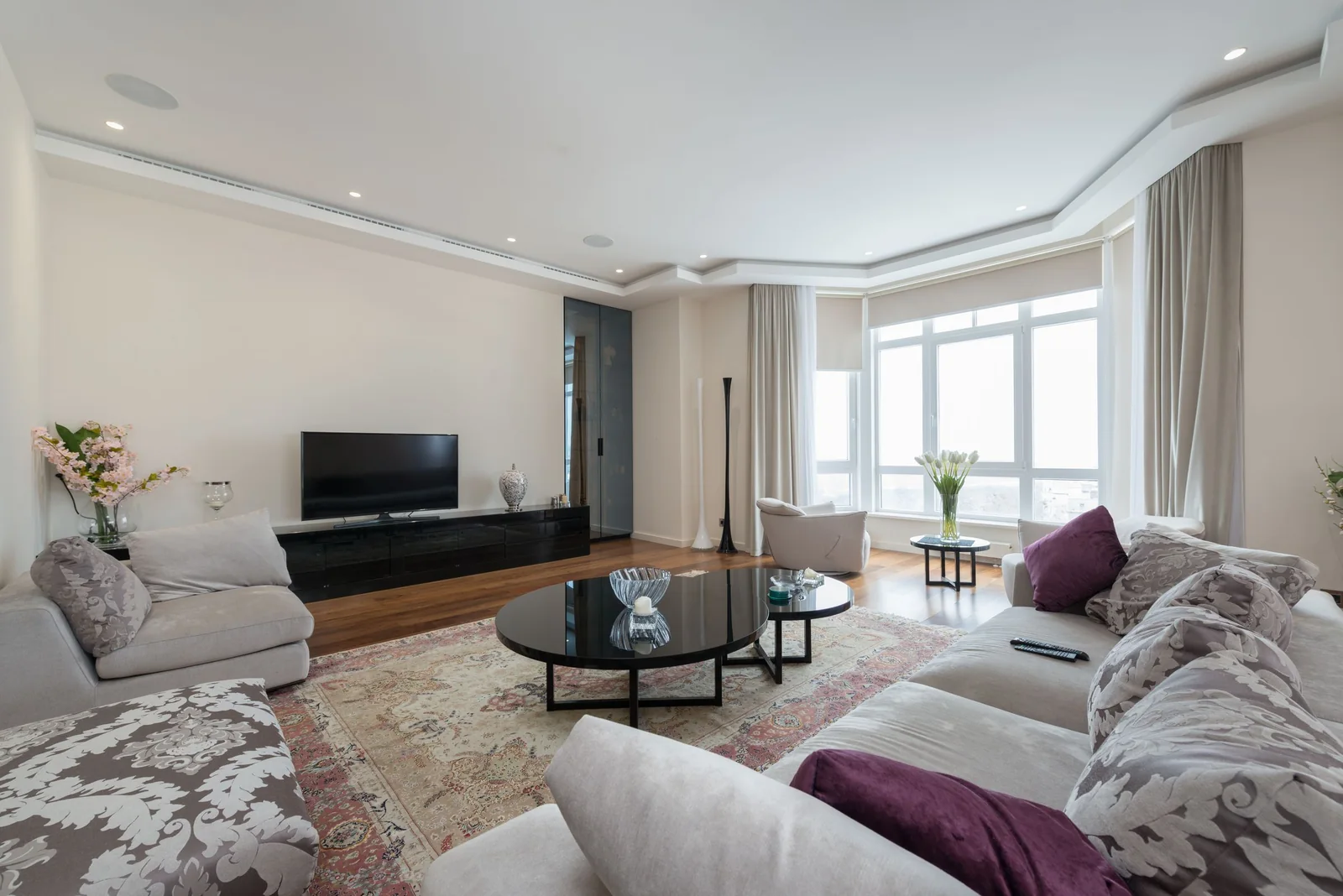A living room with a TV and big bright windows