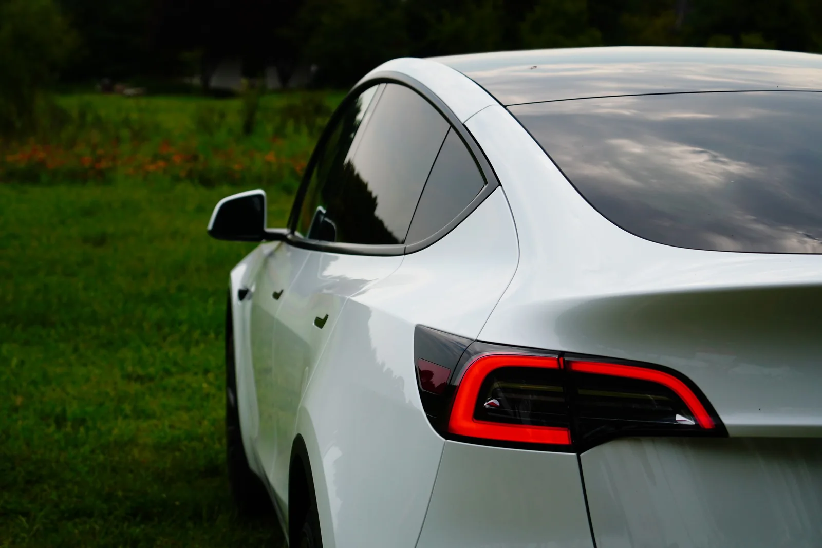 A white Tesla Model Y with dark tinted rear glass