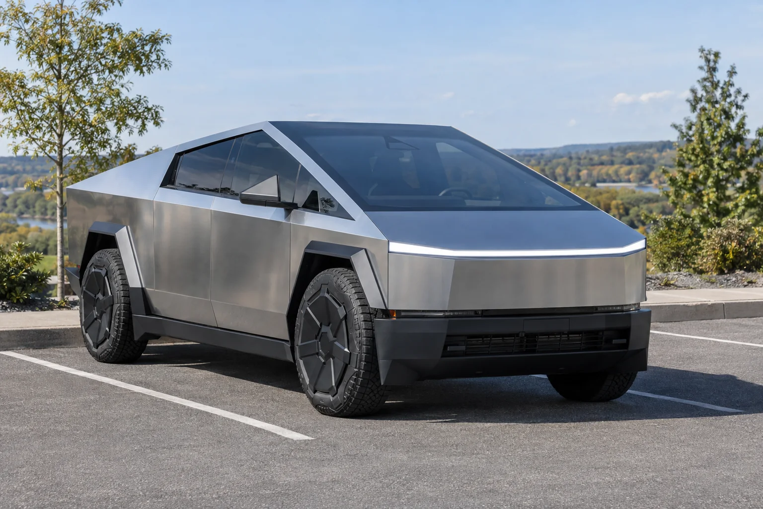 A stainless Tesla Cybertruck with tinted windows parked above a river valley