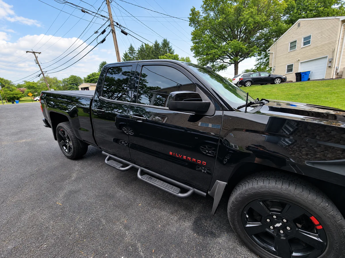 A black Chevrolet Silverado with tinted windows on a driveway