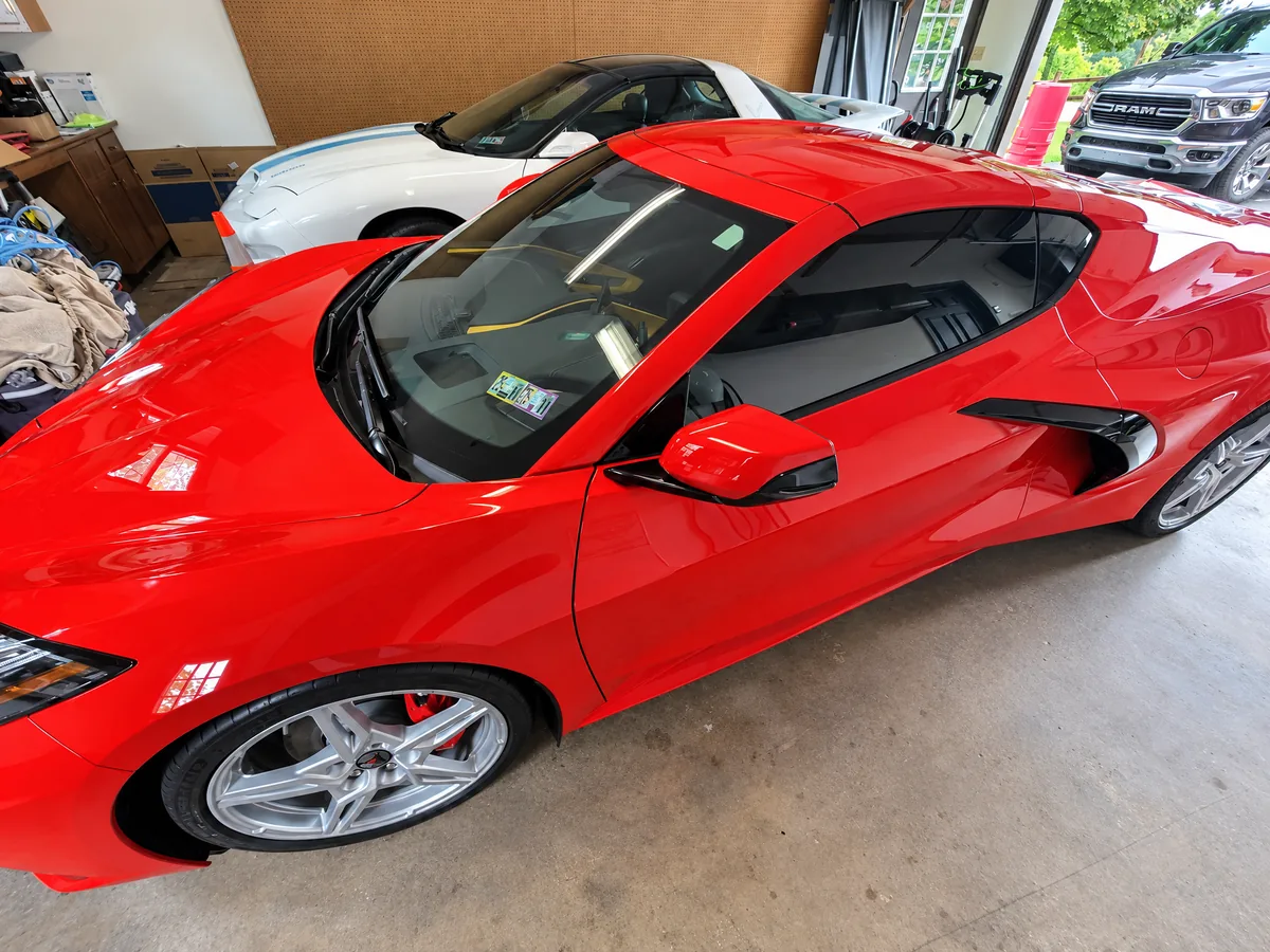 A red Chevrolet Corvette C8 with a tinted windshield strip and side glass