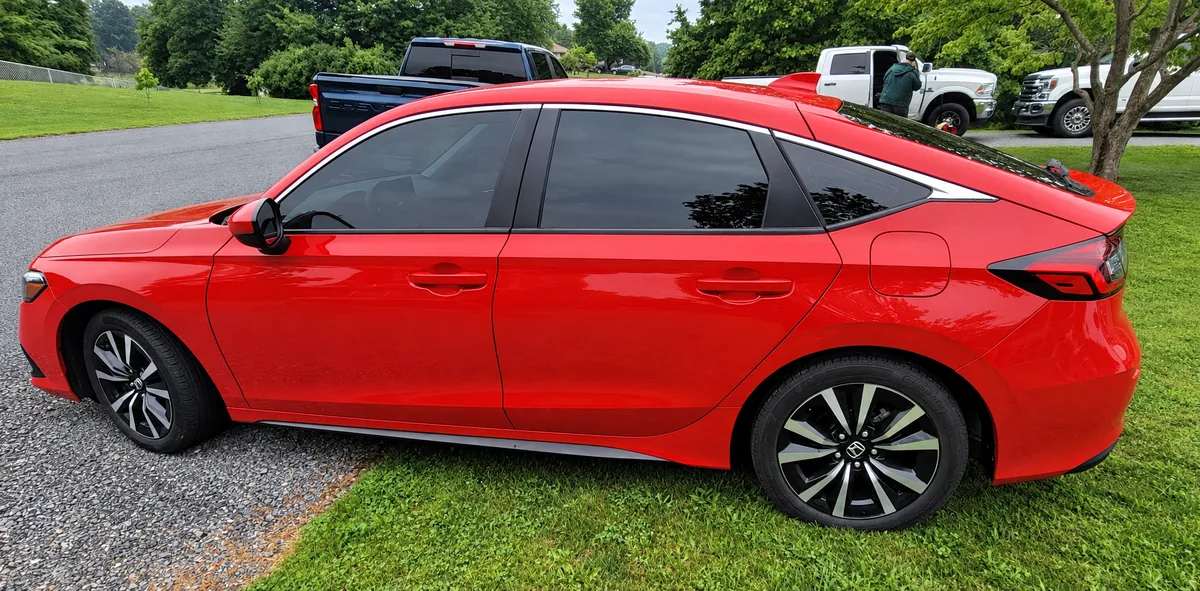 A red Honda Civic with tinted windows on a lawn